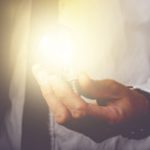 Man Holding Lit Lightbulb